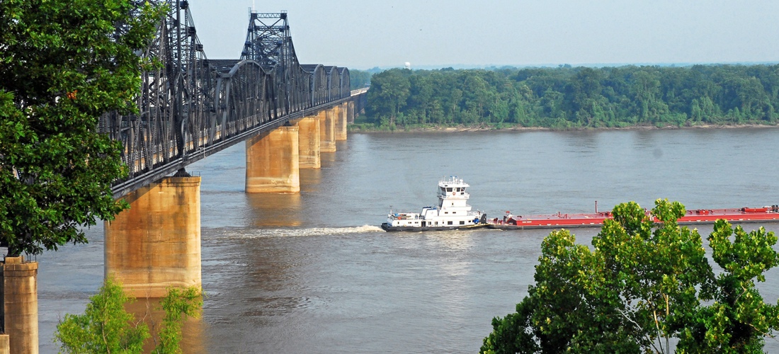 Vicksburg bridge over the Mississippi River with a passing barge.