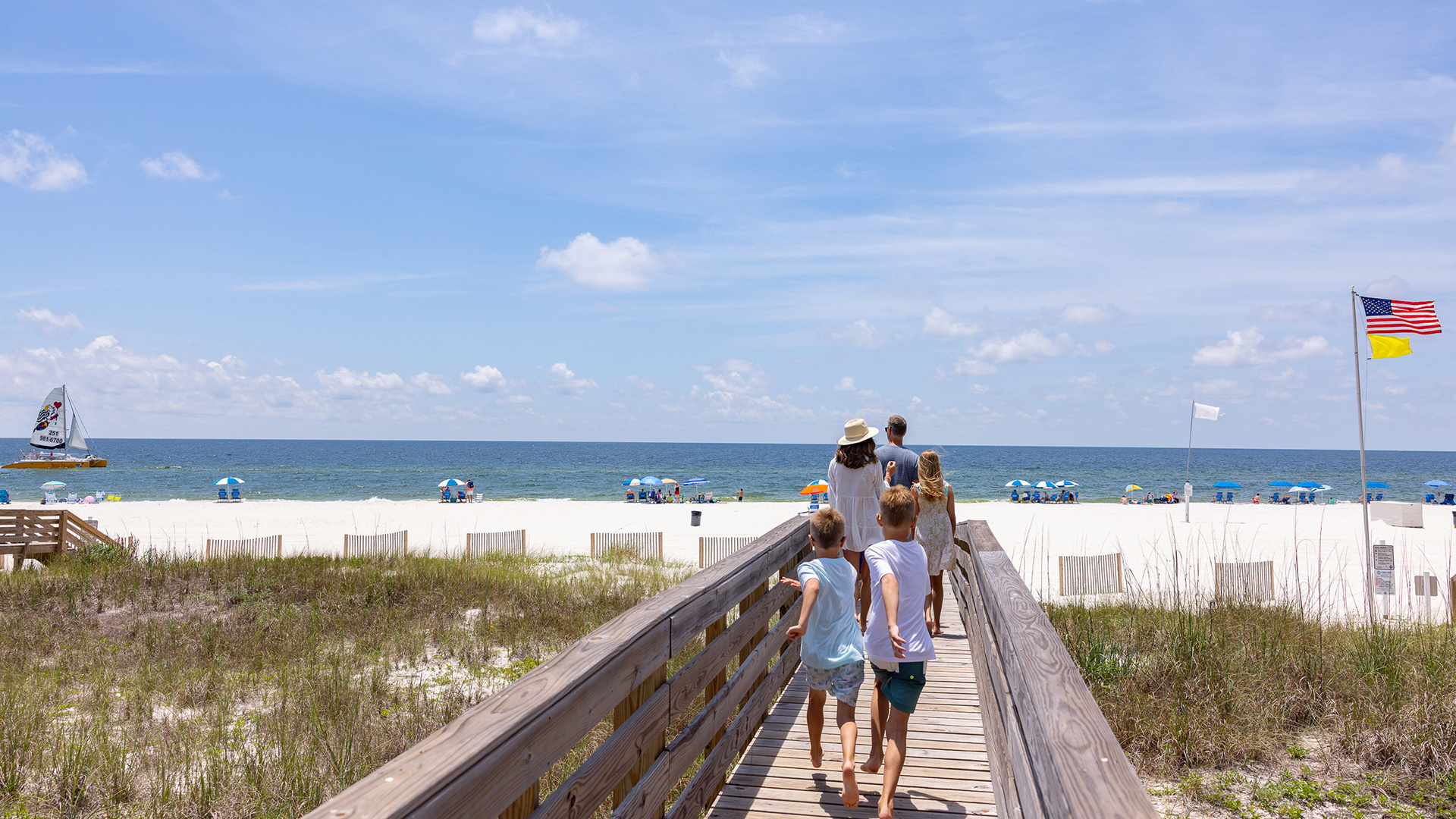 Family on a boardwalk walking to the beach in Gulf Shores, Alabama