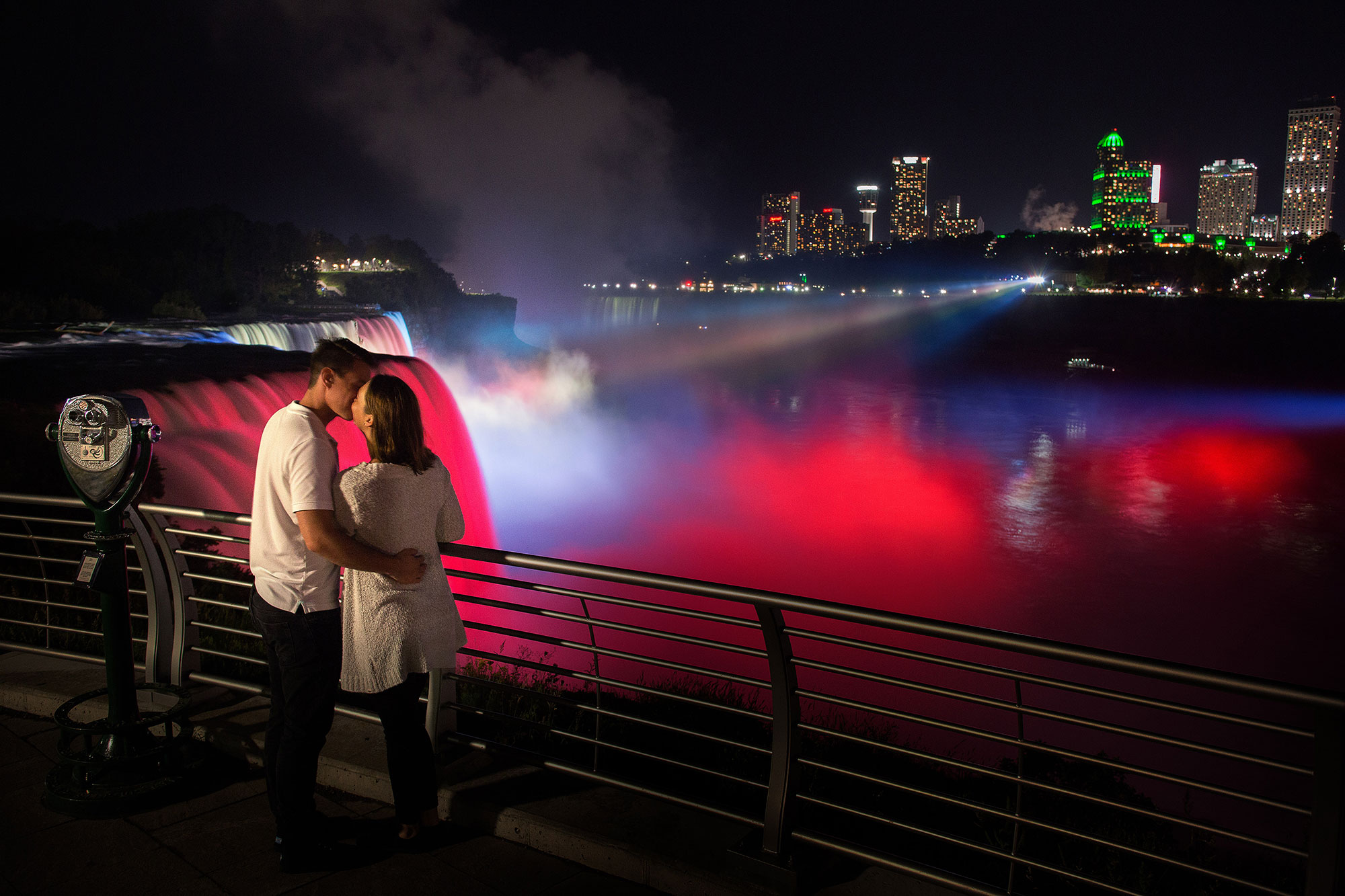 Couple kissing in front of the illuminated falls in Niagara Falls, New York.