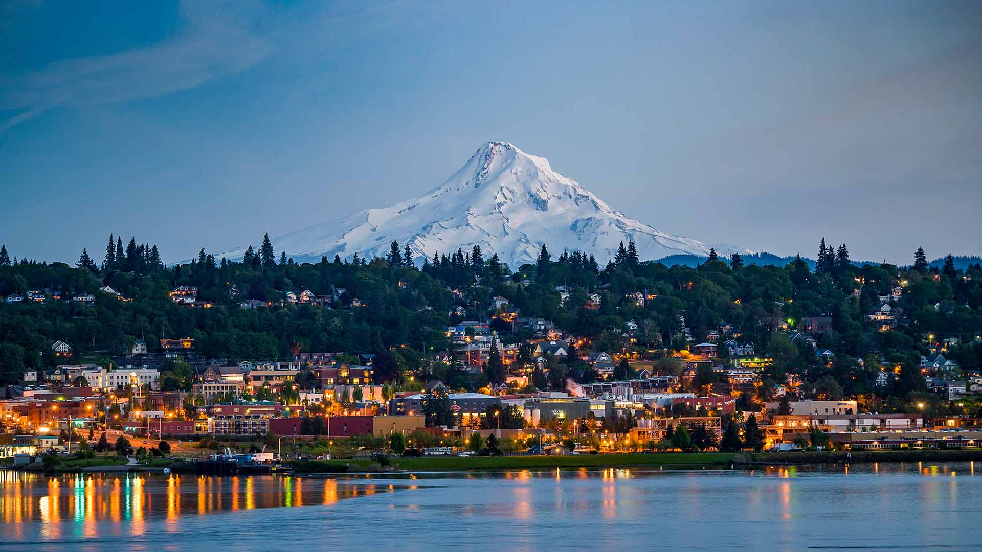 Panoramic view of Mt. Hood and the Columbia River Gorge in Oregon’s Mt. Hood Territory, with buildings aglow in twilight; Credit: hood-gorge.com